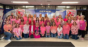 Teachers in pink smiling for a group photo